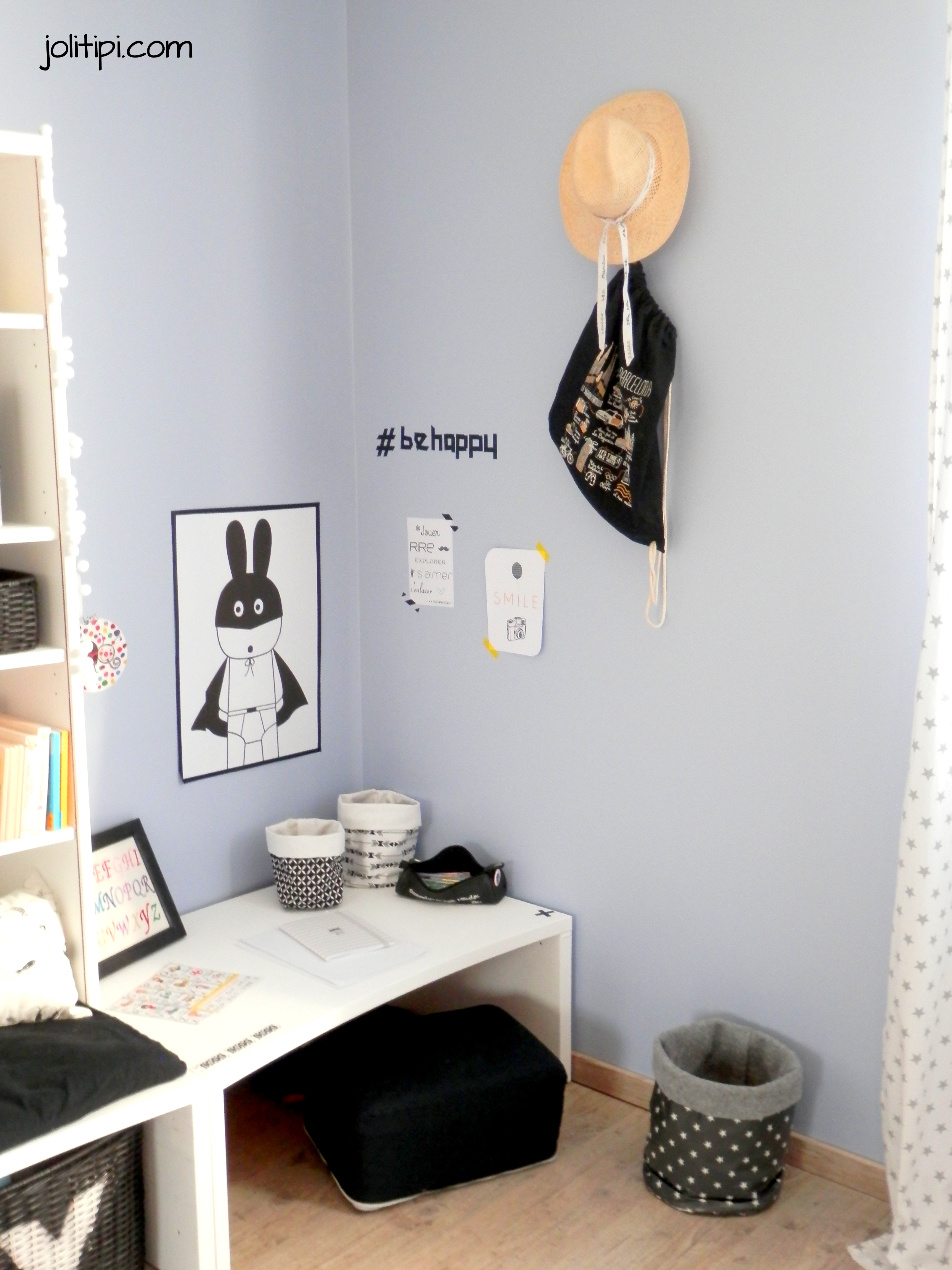 petit coin bureau dan une chambre d'enfant black and white, pouf noir, paniers en tissus motifs graphiques, affiche lapin super héro